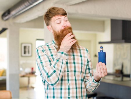Photo for Red hair man smiling with a happy, confident expression with hand on chin with a vaper - Royalty Free Image