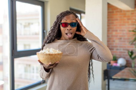 Téléchargez les photos : Noir afro femme regardant heureux, étonné et surpris avec popcorns - en image libre de droit