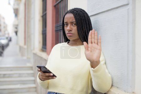 Foto de Negro afro mujer buscando grave mostrando abierta palma haciendo stop gesto. usando un concepto de smartphone - Imagen libre de derechos