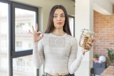 Foto de Bastante joven modelo sintiéndose feliz, mostrando aprobación con buen gesto. concepto de cookies caseras - Imagen libre de derechos