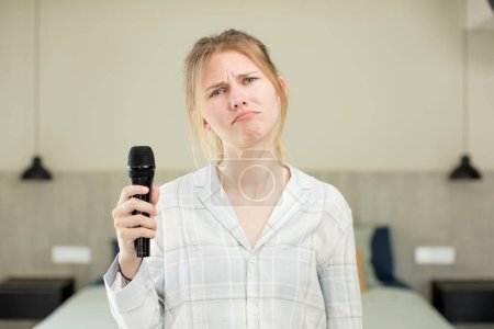 Photo for Young pretty woman feeling sad and whiney with an unhappy look and crying. microphone concept - Royalty Free Image