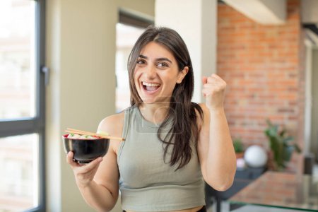 Photo for Young woman feeling shocked,laughing and celebrating success. ramen bowl - Royalty Free Image