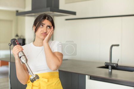 Photo for Young woman feeling bored, frustrated and sleepy after a tiresome. chef with hand blender - Royalty Free Image
