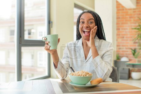 Téléchargez les photos : Afro noir femme se sentant heureux et étonné de quelque chose d'incroyable. concept de petit déjeuner - en image libre de droit