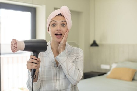 Photo for Young pretty woman feeling happy and astonished at something unbelievable. hair dryer concept - Royalty Free Image