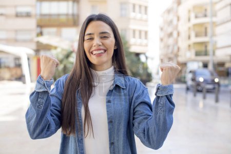 Photo for Pretty young adult woman shouting aggressively with an angry expression or with fists clenched celebrating success - Royalty Free Image