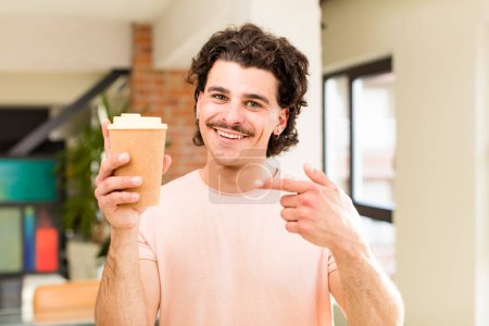 Téléchargez les photos : Jeune bel homme tenant une boisson au café chaud à l'intérieur de la maison - en image libre de droit