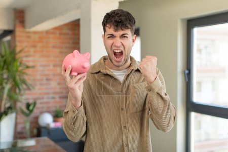 Photo for Young handsome man looking angry, annoyed and frustrated. piggy bank concept - Royalty Free Image