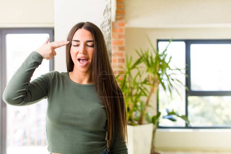 Photo for Young adult pretty woman looking unhappy and stressed, suicide gesture making gun sign with hand, pointing to head - Royalty Free Image