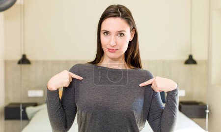 Photo for Young adult pretty woman looking proud, positive and casual pointing to chest with both hands - Royalty Free Image
