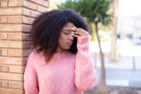Foto de Mujer bonita afroamericana sintiéndose estresada, infeliz y frustrada, tocando la frente y sufriendo migraña de dolor de cabeza severo - Imagen libre de derechos