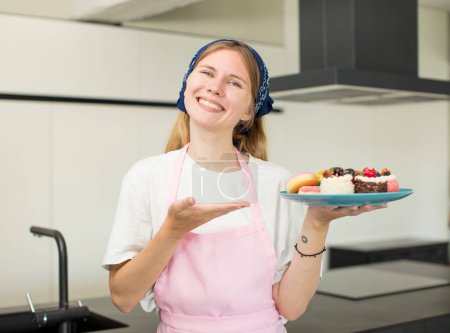 Photo for Young pretty woman smiling cheerfully, feeling happy and showing a concept. home made cakes concept - Royalty Free Image
