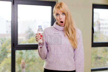 Foto de Joven bonita mujer con una botella de agua en el interior de casa - Imagen libre de derechos