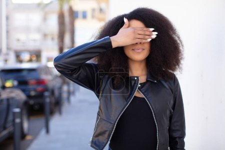 Photo for African american pretty woman covering eyes with one hand feeling scared or anxious, wondering or blindly waiting for a surprise - Royalty Free Image