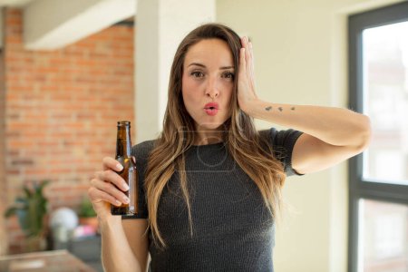 Photo for Pretty woman feeling extremely shocked and surprised. beer bottle - Royalty Free Image