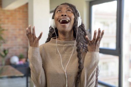 Téléchargez les photos : Noir afro femme crier avec les mains en l'air. concept de musique d'écoute - en image libre de droit