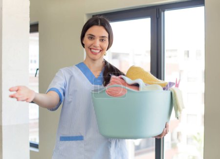 Photo for Pretty young model smiling happily and offering or showing a concept. housekeeper and laundry concept - Royalty Free Image