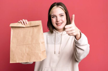 Téléchargez les photos : Young pretty woman with a take away paper bag - en image libre de droit