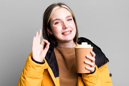 Téléchargez les photos : Young pretty woman with a coat and a take away coffee - en image libre de droit