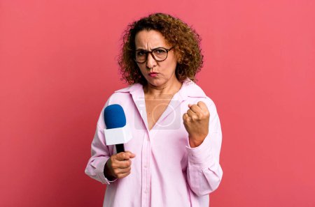 Photo for Pretty middle age woman feeling angry, annoyed, rebellious and aggressive. tv presenter with a microphone concept - Royalty Free Image