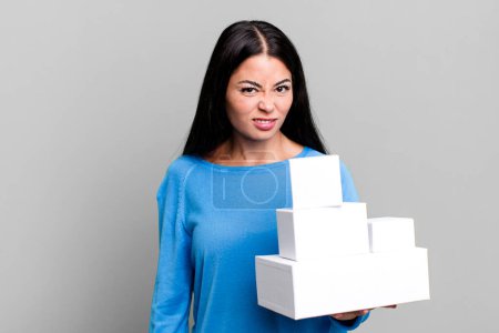 Téléchargez les photos : Hispanique jolie femme se sentant perplexe et confus. avec emballages de boîtes blanches - en image libre de droit