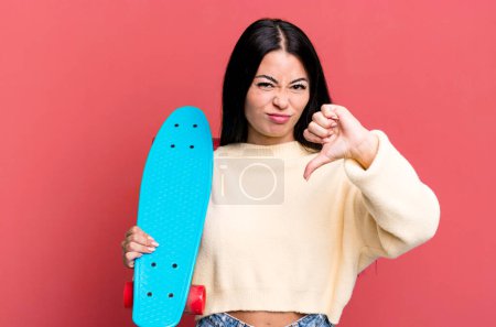 Photo for Hispanic pretty woman feeling cross,showing thumbs down. skate boarding concept - Royalty Free Image