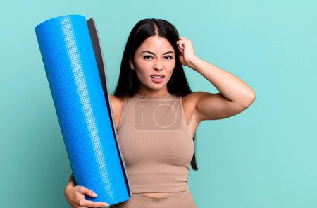 Téléchargez les photos : Hispanique jolie femme se sentant confus et perplexe, montrant que vous êtes fou concept de yoga - en image libre de droit