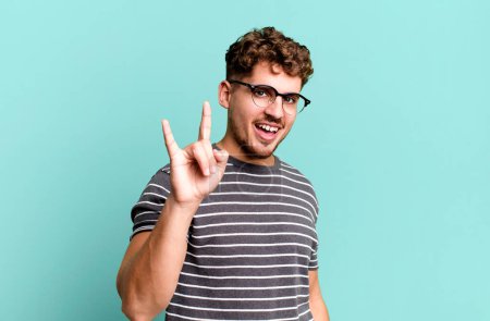 Photo for Young adult caucasian man feeling happy, fun, confident, positive and rebellious, making rock or heavy metal sign with hand - Royalty Free Image