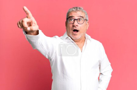 Photo for Middle age senior man feeling shocked and surprised, pointing and looking upwards in awe with amazed, open-mouthed look - Royalty Free Image