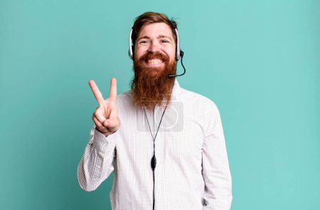 Téléchargez les photos : Barbe longue homme souriant et l'air amical, montrant numéro deux. concept d'agent de télémarketing - en image libre de droit
