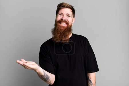 Téléchargez les photos : Longue barbe et cheveux roux homme souriant joyeusement, se sentant heureux et montrant un concept - en image libre de droit