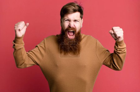 Téléchargez les photos : Barbe longue et cheveux roux homme criant agressivement avec une expression en colère - en image libre de droit