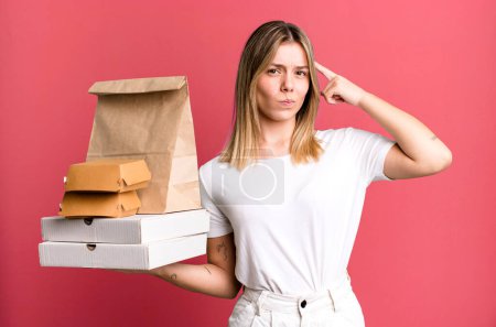 Photo for Young pretty woman feeling confused and puzzled, showing you are insane. delivery and take away food concept - Royalty Free Image