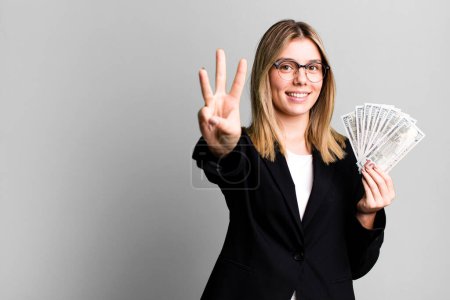 Foto de Joven bonita mujer sonriendo y buscando amigable, mostrando el número tres. concepto de negocio y dinero - Imagen libre de derechos