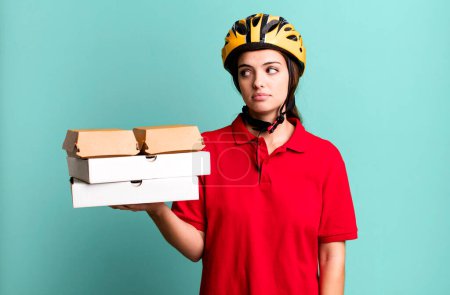 Téléchargez les photos : Young pretty woman on profile view thinking, imagining or daydreaming. pizza delivery concept - en image libre de droit