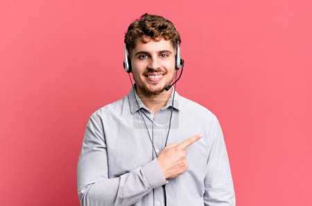 Photo for Young adult caucasian man smiling cheerfully, feeling happy and pointing to the side. telemarketer agent concept - Royalty Free Image