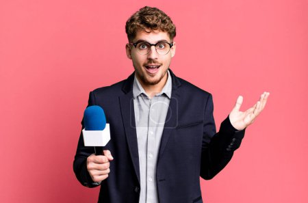 Photo for Young adult caucasian man feeling happy, surprised realizing a solution or idea. journalist or presenter with a microphone - Royalty Free Image