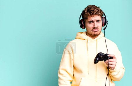 Photo for Young adult caucasian man feeling sad and whiney with an unhappy look and crying with headset and a controller. gamer concept - Royalty Free Image