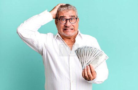 Photo for Middle age senior man feeling stressed, anxious or scared, with hands on head. dollar banknotes concept - Royalty Free Image