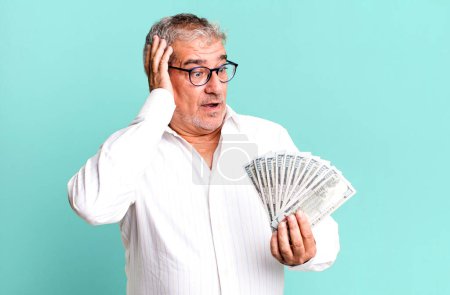 Foto de Hombre mayor de mediana edad sintiéndose feliz, emocionado y sorprendido. concepto de billetes en dólares - Imagen libre de derechos
