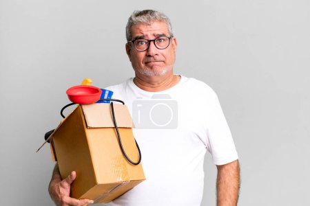 Foto de Hombre mayor de mediana edad mirando perplejo y confundido. ama de llaves reparador con un concepto de caja de herramientas - Imagen libre de derechos