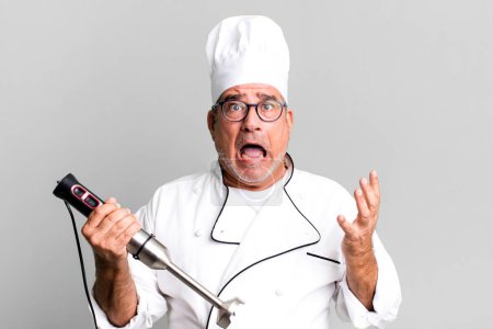 Photo for Middle age senior man looking desperate, frustrated and stressed. restaurant chef with a tool concept - Royalty Free Image