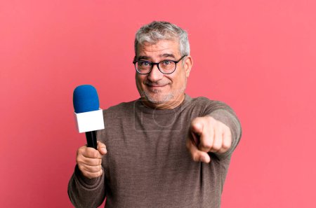 Photo for Middle age senior man pointing at camera choosing you. journalist or tv presenter with a micro - Royalty Free Image