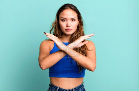 Photo for Young pretty woman looking annoyed and sick of your attitude, saying enough! hands crossed up front, telling you to stop - Royalty Free Image