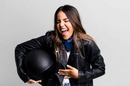 Téléchargez les photos : Jolie femme hispanique riant à haute voix à une blague hilarante. concept de motocycliste - en image libre de droit