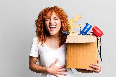 Photo for Red hair pretty woman laughing out loud at some hilarious joke. housekeeper and toolbox concept - Royalty Free Image