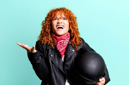 Téléchargez les photos : Cheveux roux jolie femme à l'air désespéré, frustré et stressé. concept de motocycliste - en image libre de droit