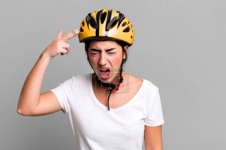 Photo for Looking unhappy and stressed, suicide gesture making gun sign. bike helmet concept - Royalty Free Image
