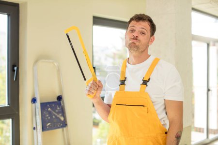 Photo for Feeling sad and whiney with an unhappy look and crying. handyman saw concept - Royalty Free Image
