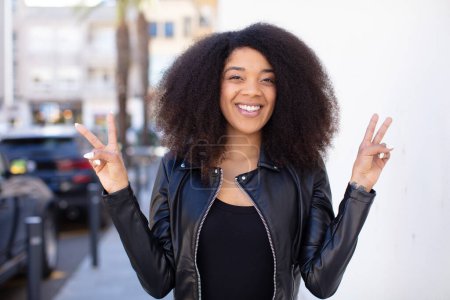 Photo for African american pretty woman smiling and looking happy, friendly and satisfied, gesturing victory or peace with both hands - Royalty Free Image